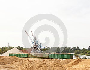 The port crane makes loading of wood chips into the freight cars of the train, loading