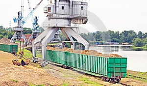 The port crane makes loading of wood chips into the freight cars of the train, loading