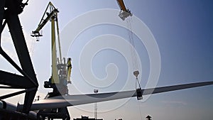 Port crane unloads the huge blades and propeller of a wind turbine onto a wharf. Green wind turbine energy and eco