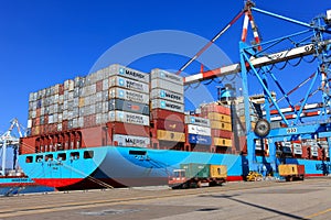 Port dock with container ship and Various brands and colors of shipping containers stacked in a holding platform