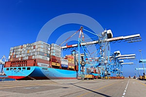 Port dock with container ship and Various brands and colors of shipping containers stacked in a holding platform