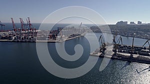 Port industry, drone view of trading sea harbor with containers and lifting cranes on Sea coast against blue sky and