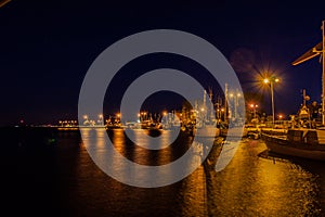 Port in night lighting, light reflections in water