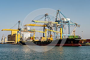 Container ship under flag of Liberia being loaded with containers and cargo in port in Port Sudan.