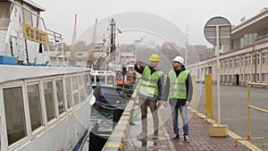 Port workers in helmets talking near the boat