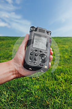 Portable audio recorder in hand field recording ambient sounds