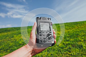 Portable audio recorder in hand field recording ambient sounds of nature