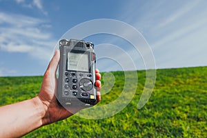 Portable audio recorder in hand field recording ambient sounds of nature