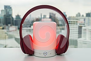 Portable Bluetooth speaker in red color with cute pink wireless headphones for pairing to listen to music photo