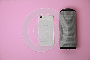 Portable bluetooth speaker and smartphone on pink background, flat lay with space for text. Audio equipment