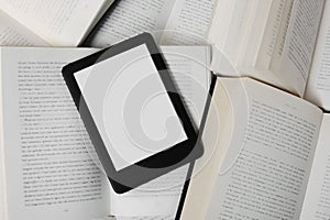 Portable e-book reader on different open books, top view