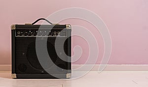 Portable electric guitar amplifier isolated in front of a stone wall, music equipment background