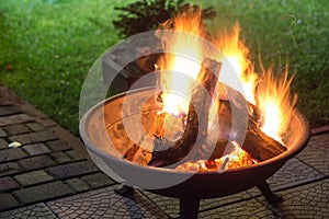 A portable fireplace with bright burning firewoods making sparks