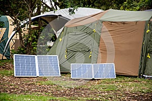 Portable foldable solar panels and Tent at the campsite surrounding by nature. Camping and recreation