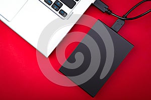 A portable hdd connected to a laptop on a red background