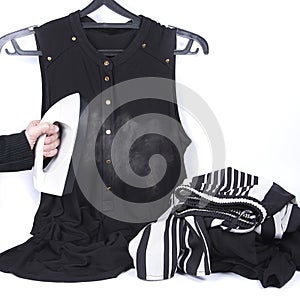 Portable home and garment steamer for clothes and black blouse on hanger isolated on white background. Clothes pile. Female hand