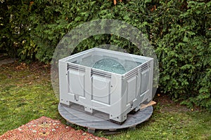 Portable plastic bath tub or tank in a garden ready for ice bathing in the cold water filled with ice cubes