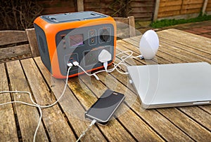 Portable power station solar electricity generator with multiple devices charging. Side angle view.