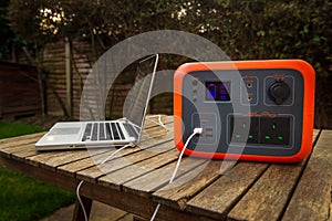 Portable power station solar electricity generator outdoors with laptop plugged in charging.