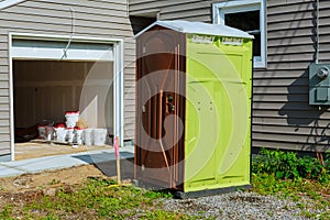 Portable restroom on a new structure near new house under construction.