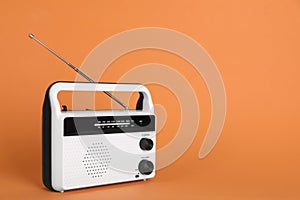 Portable retro radio receiver on orange background. Space for text