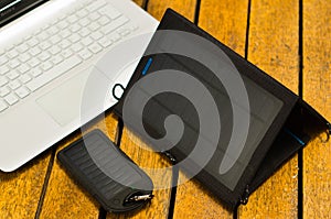 Portable solar chargers sitting on wooden surface next to laptop computers, as seen from above, modern technology