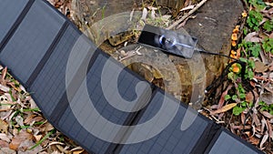 portable solar panel charging smartphone by mutlipurpose cable, power bank, watches, laptops nature background. Clean