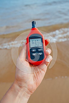 Portable thermometer in hand measuring outdoor air temperature and humidity