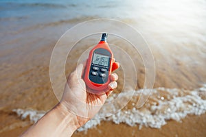 Portable thermometer in hand measuring outdoor air temperature and humidity