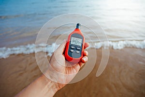 Portable thermometer in hand measuring outdoor air temperature and humidity