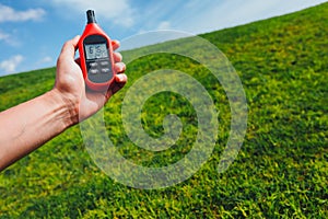 Portable thermometer in hand measuring outdoor air temperature and humidity