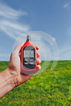 Portable thermometer in hand measuring outdoor air temperature and humidity