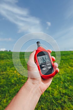 Portable thermometer in hand measuring outdoor air temperature and humidity