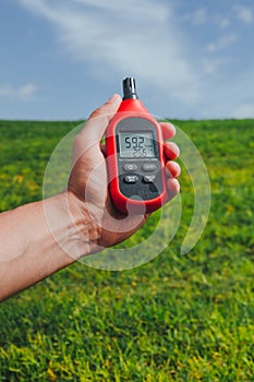 Portable thermometer in hand measuring outdoor air temperature and humidity