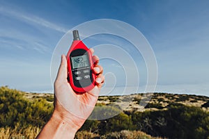 Portable thermometer in hand measuring outdoor air temperature and humidity