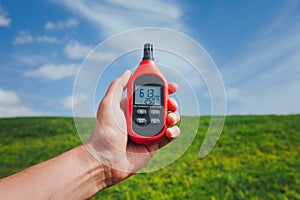 Portable thermometer in hand measuring outdoor air temperature and humidity