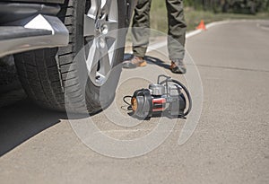 Portable tire pump for inflating car wheel on road. Tyre inflator air compressor with manometer