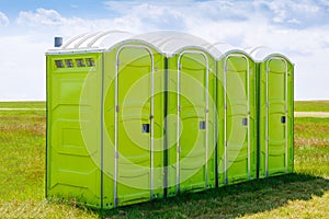 Portable toilet on the grass on a background of clouds