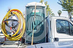 Portable toilet with pump loaded over small truck photo