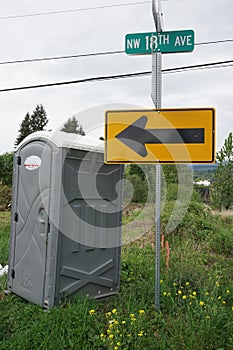 Portable Toilet at street corner with sign pointing to it