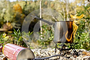 Portable tourist gas stove with a gray kettle on a background of nature in the mountains. Camping kitchen and tea