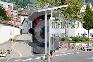 Portable traffic light powered by solar panels situated on the road to guide traffic during construction work.