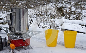 Portable travel gas stove with a cup in the snow in winter. Traditional cuisine and tea making.