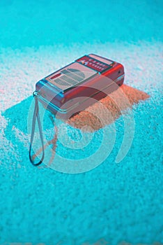 Portable vintage transistor lying on white carpet.