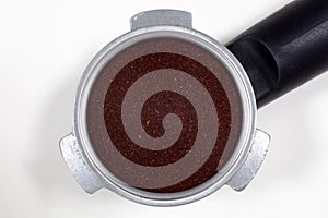 Portafilter filled with ground coffee on a white background