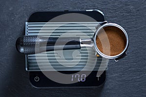 Portafilter with freshly ground morning coffee on the scales
