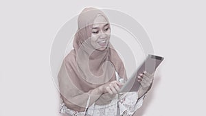 Portait of asian muslim woman wearing head scarf or hijab playing with tablet pc