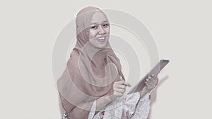 Portait of asian muslim woman wearing head scarf or hijab playing with tablet pc