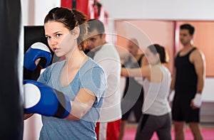 Portait of girl which is beating a boxing bag