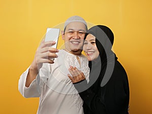 Portait of happy Asian muslim couple making selfie and smiling, husband and wife hugging full of love, family